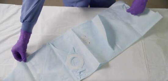 Un professionnel de la santé qui étend une Couverture sous patient pédiatrique Bair Hugger(MC) 3M(MC).
