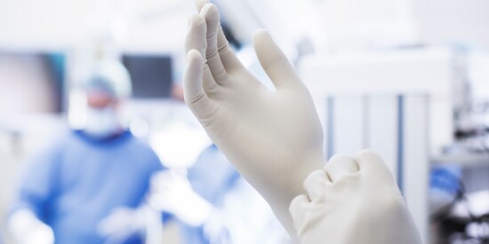 Health care professional putting on white sterile gloves before surgery
